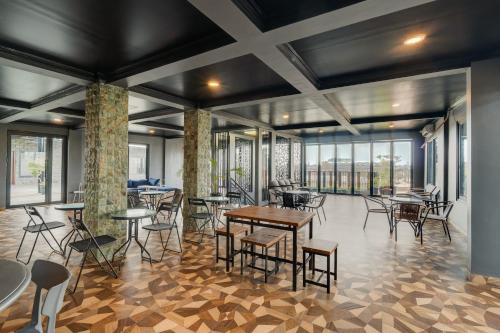 une salle à manger avec tables, chaises et fenêtres dans l'établissement YASA Residence Fatmawati, à Jakarta