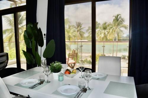 a white table with plates and glasses and a view of the ocean at Stylish 2BR in Hawana Salalah with Beautiful Balcony in Wādī Khasbar