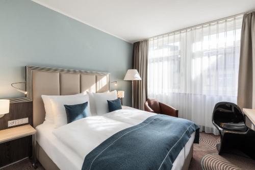 a hotel room with a bed and a chair at Garner Hotel Essen - Handelshof by IHG in Essen
