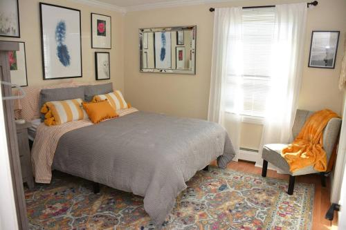 a bedroom with a bed and a chair and a window at Little Miss Cottages - 68 East Grand Luxury Condo in Old Orchard Beach
