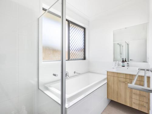 une salle de bain blanche avec une baignoire et un lavabo dans l'établissement Bright Serenity Family Comfort near Parks and Shops, à Marsden