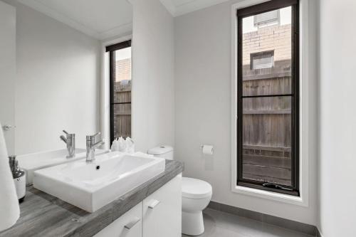 a white bathroom with a sink and a toilet at Modern Comfort Patio and Workstation with Garage in North Lakes