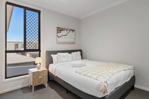 a white bedroom with a large bed and a window at Modern Comfort Patio and Workstation with Garage in North Lakes