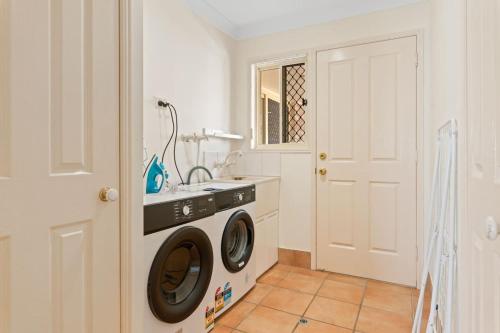 a laundry room with a washing machine and a sink at Spacious 4BR Family Home in Capalaba Local Charm in Capalaba