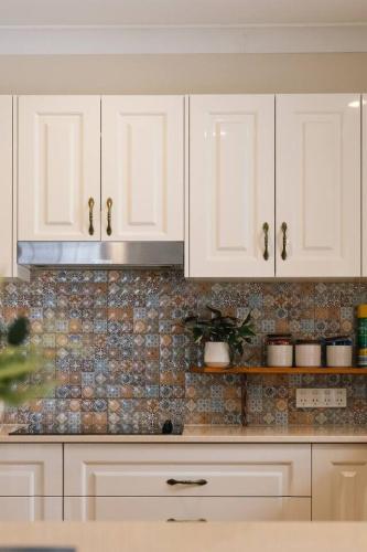 a kitchen with white cabinets and a tile wall at Spacious 4BR Family Home in Capalaba Local Charm in Capalaba