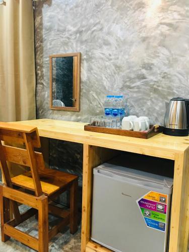 a wooden table with a wooden chair next to a refrigerator at Baan Sangchan in Ko Kood