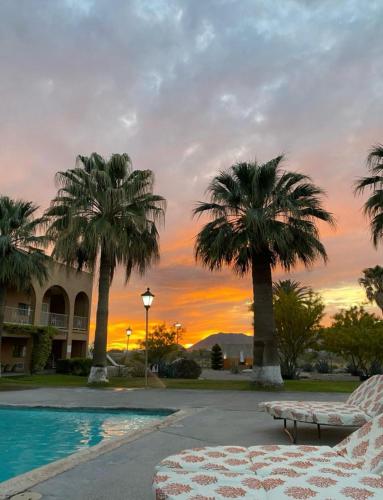 a resort with palm trees and a pool with a sunset at Hotel Santa Fe in Camargo