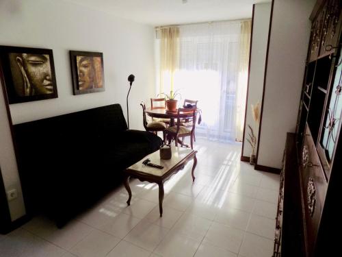 a living room with a black couch and a table at Alojamiento AJO con piscina y tenis - Ajo Palace in Ajo