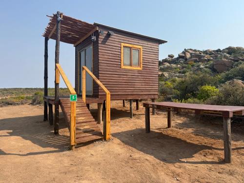 a wooden cabin with a bench and a picnic table at Dakotas offgrid camping in Springbok