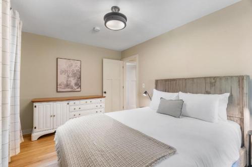 a bedroom with a large white bed and a dresser at Woodland Hollow in Minnetonka