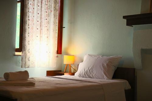 a bedroom with a bed with a window and a lamp at Το Περάντι - Επιπλωμένη Οικία Guesthouse in Doliana