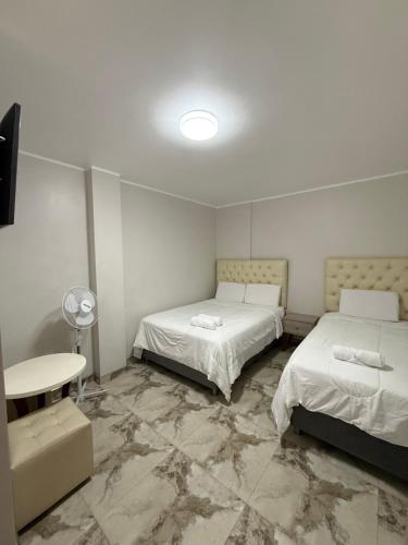 a room with two beds and a table in it at Nayarak Paracas in Paracas