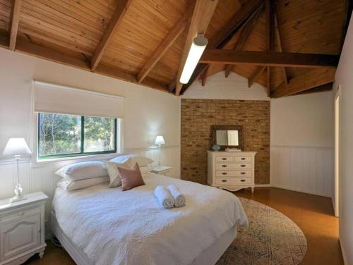 a bedroom with a large bed with two pillows on it at Sandys Pottery Cottage- pet friendly, wineries, in Healesville
