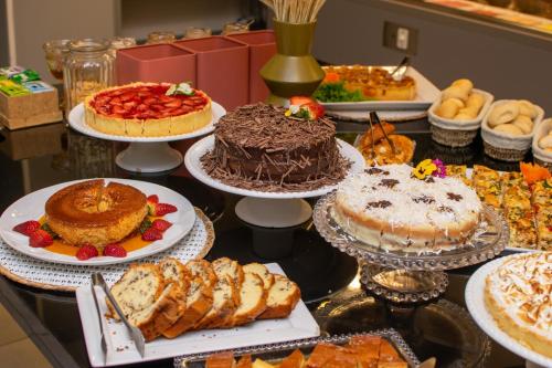 a table full of cakes and pastries on plates at Eleganz Suítes Exclusive Centro in Gramado