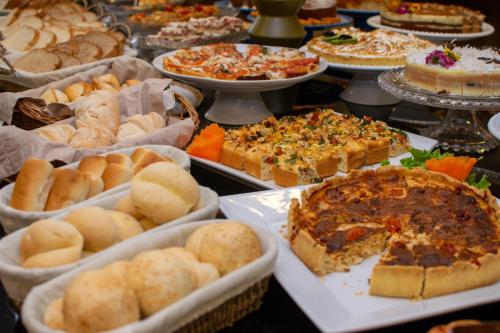 a table full of different types of bread and pies at Eleganz Suítes Exclusive Centro in Gramado
