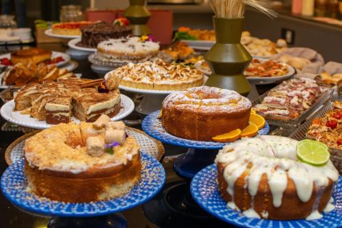 a table full of cakes and pies on plates at Eleganz Suítes Exclusive Centro in Gramado