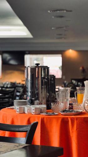 a table with an orange table cloth with a coffee maker on it at Hotel " Rio Grande " in Malargüe