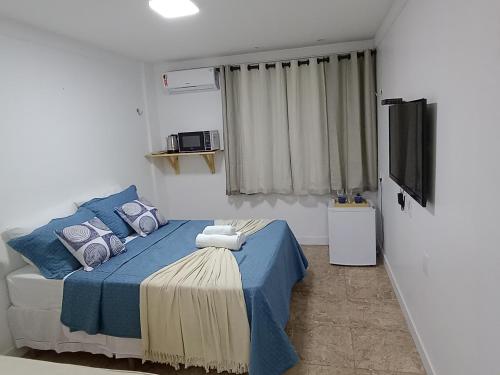 sypialnia z niebieskim łóżkiem i telewizorem z płaskim ekranem w obiekcie Apartamento a beira mar w mieście Natal