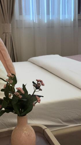 a vase with flowers on a table next to a bed at Al Marsa in Al Ashkharah