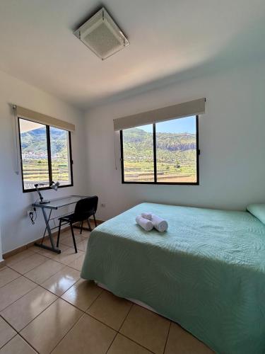 a bedroom with a bed and a desk and windows at Apartamento tranquilo con vistas in Los Realejos