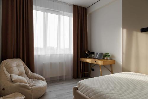 a bedroom with a bed and a chair and a window at Modern 2-BR Balcony-View Apartment with Coffee Station and more - GrandStay in Chişinău