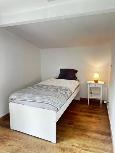a white bed in a white room with a table at Ottignies Apartment in Louvain-la-Neuve