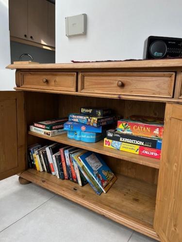a wooden book shelf with many books on it at Ottignies Apartment in Louvain-la-Neuve