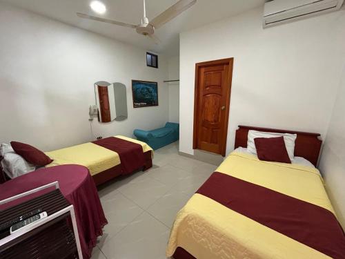 a room with two beds and a tv in it at Hostal Sir Francis Drake in Puerto Ayora