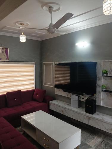 ein Wohnzimmer mit einem roten Sofa und einem Flachbildfernseher in der Unterkunft The family courtyard in Amritsar