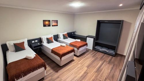 a room with two beds and a flat screen tv at Eco Park Campo Grande Hotel in Campo Grande
