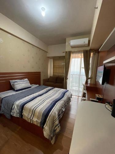 a bedroom with a bed and a couch and a television at The Avenue Parkland Serpong by Ngeroomin in Babakan