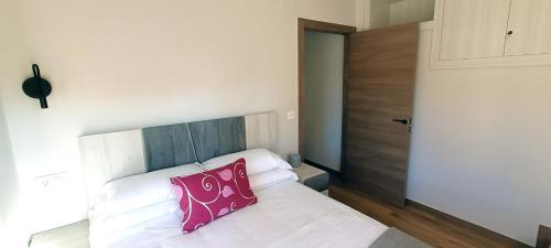 a bedroom with a white bed with a pink pillow at Apartamentos EL PUENTE in Covarrubias