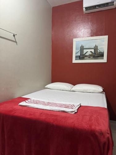 a bedroom with a bed with a red wall at PORTO PLAZA POUSADA in Barcarena