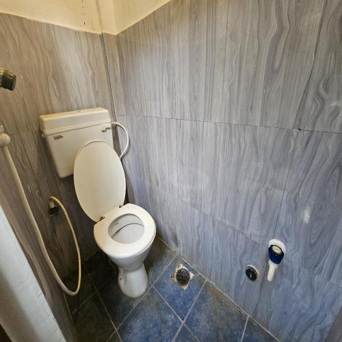 a bathroom with a white toilet in a room at Aurobay Resorts Pondicherry in Auroville