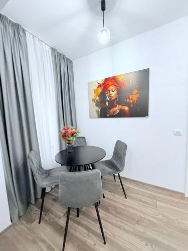 a dining room with a table and chairs and a painting at Harmony Apartments Airport in Iaşi