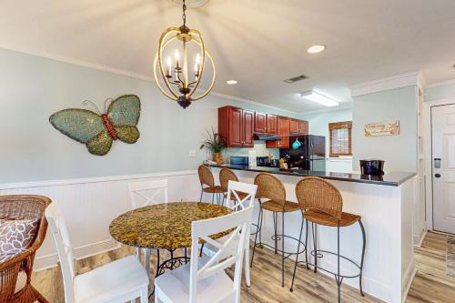 a kitchen with a table with chairs and a butterfly on the wall at Romar Beach 205 in Gulf Shores