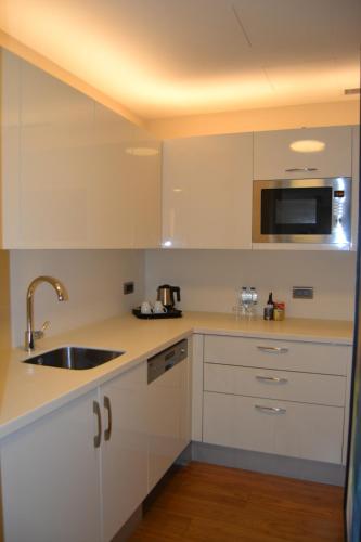 a kitchen with white cabinets and a sink and a microwave at Wyndham Grand Istanbul Europe in Istanbul
