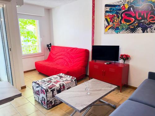 a living room with a red couch and a table at Appartement 45m2 Centre Île Rousse Plage à 100m Vue Mer in LʼÎle-Rousse