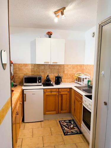 a small kitchen with wooden cabinets and white appliances at Appartement 45m2 Centre Île Rousse Plage à 100m Vue Mer in LʼÎle-Rousse
