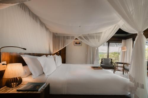 Un dormitorio con una gran cama blanca y una silla. en Txai Resort, en Itacaré