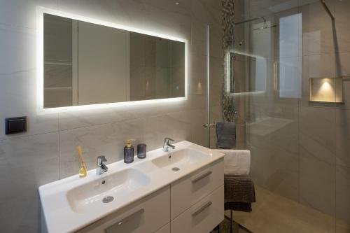 ein weißes Badezimmer mit Waschbecken und Spiegel in der Unterkunft A&M House III in Arco da Calheta