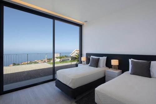 ein Schlafzimmer mit zwei Betten und einem großen Fenster in der Unterkunft A&M House III in Arco da Calheta