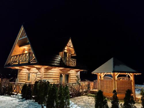 a log cabin in the snow at night at Zymbiańsko Chałupa 1 z balią na wyłączność in Ząb