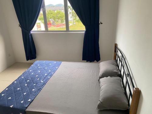 a bedroom with a bed with blue curtains and a window at Homestay TigaCahaya in Seremban
