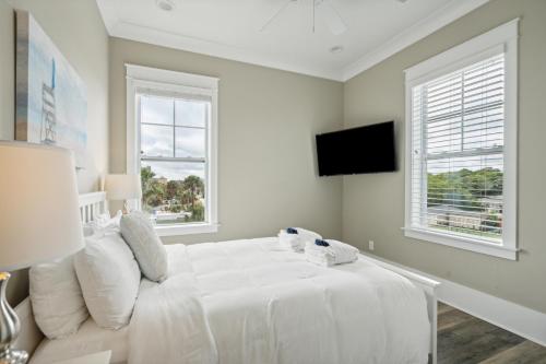 a white bedroom with a white bed and windows at 207 E Arctic - Seahorsing Around - Oceanfront - 3 Bedrooms in Folly Beach