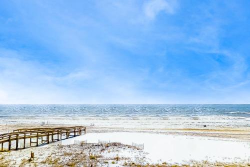a wooden pier on a beach next to the ocean at Four Winds 902 in Orange Beach