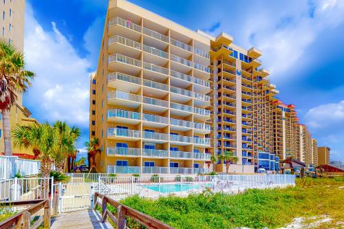 a large building with a swimming pool next to a beach at Four Winds 902 in Orange Beach