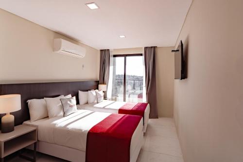 two beds in a hotel room with a window at Ramada Suites by Wyndham Asuncion Aeropuerto in Asuncion