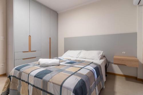 a bedroom with a bed with a striped blanket at Apto funcional no Centro de Blumenau UG6156 in Blumenau