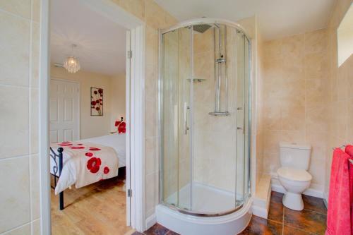 een badkamer met een douche, een toilet en een bed bij Farriers Cottage in Blofield